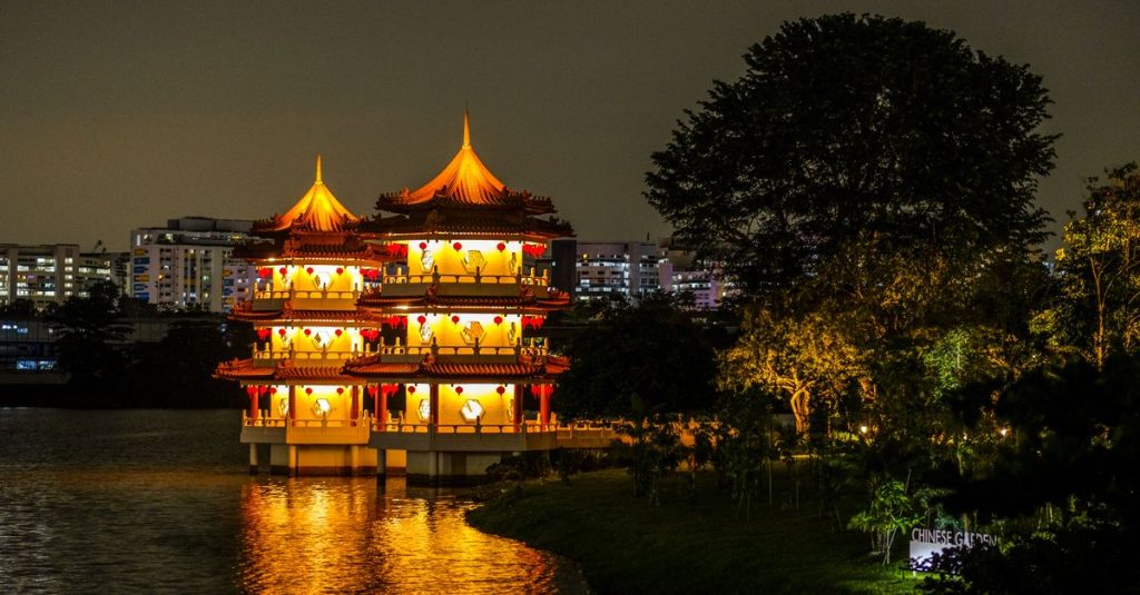 Pagodes jumelles illuminées du Chinese Garden au bord du lac, de nuit, à Singapour.