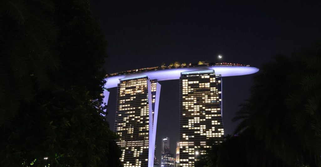 Marina Bay Sands illuminé de nuit, vu entre les arbres